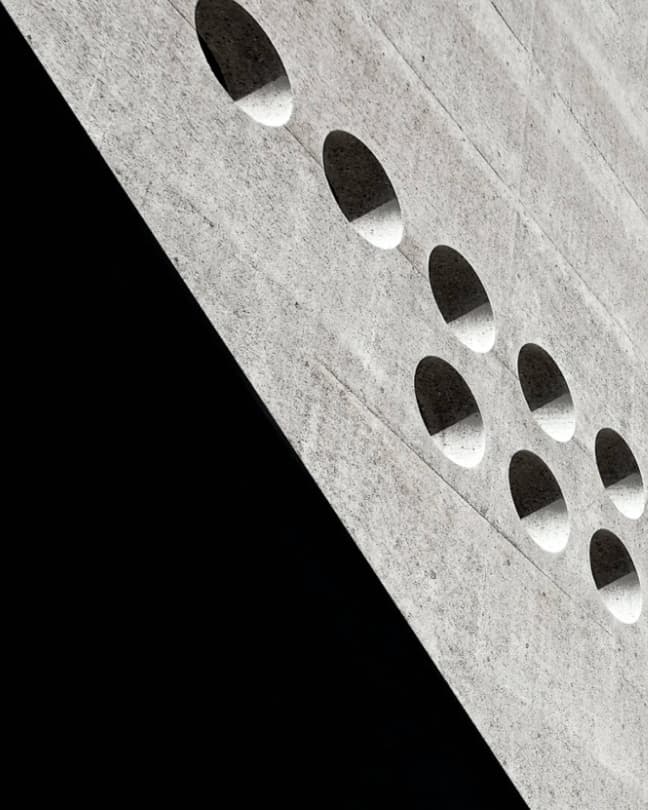 Close-up of an abstract concrete building facade showing geometric shapes and textured surfaces.