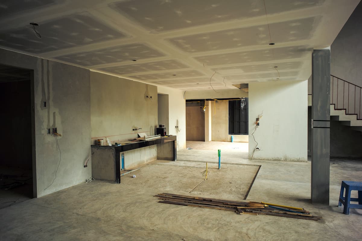 Interior view of a property under development showing unfinished walls, ceiling, and construction materials on site.