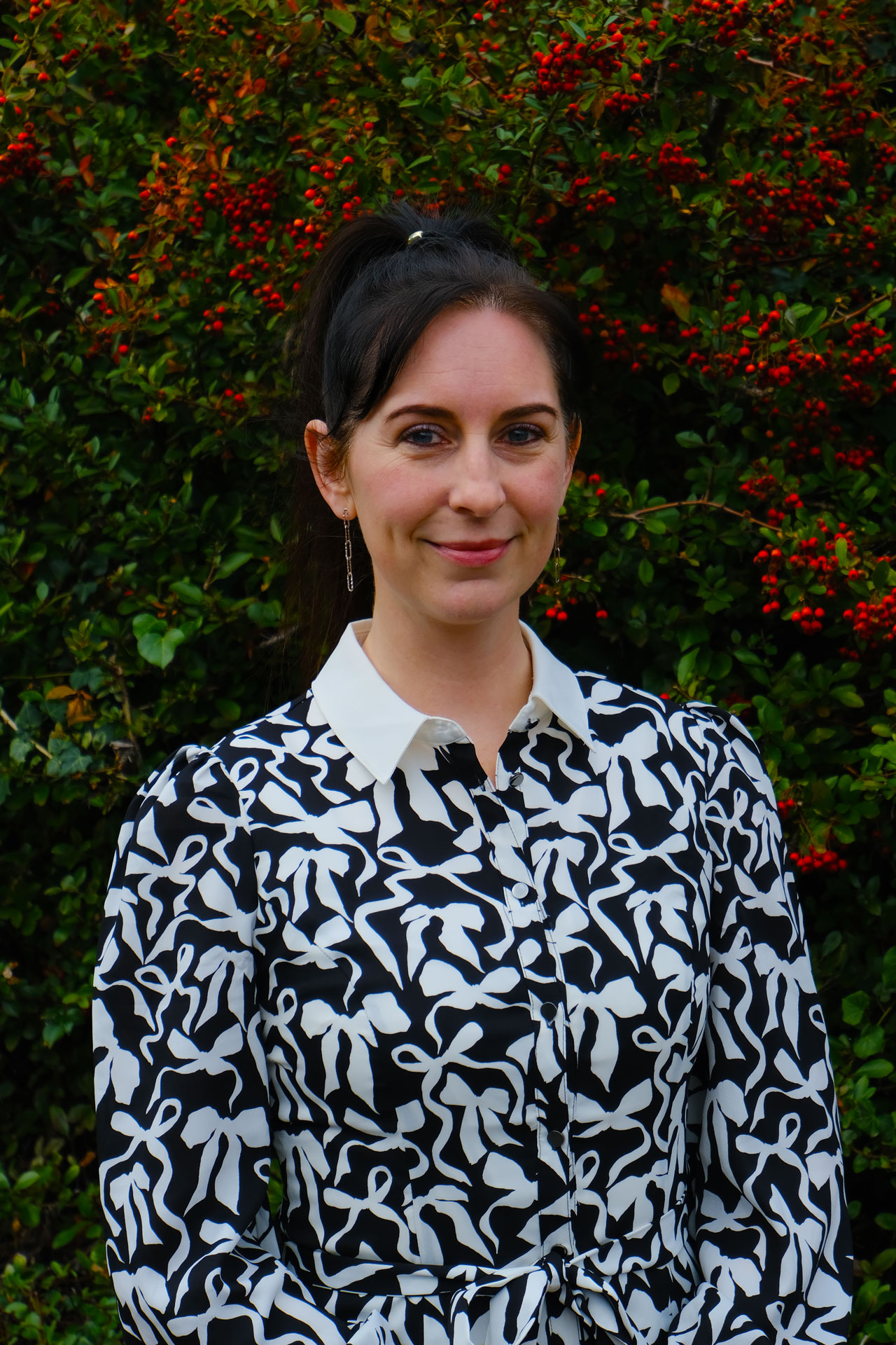 Portrait of Kerry Rose, founder of Rose Lock Property Ltd, standing outdoors in front of greenery and red berries.