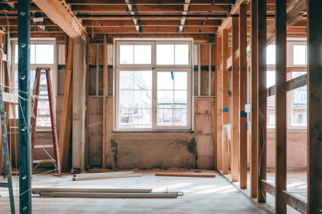 Interior view of a construction site showing exposed timber wall frames, window openings, and structural studs during the build of accessible housing.